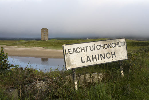 Lahinch town sign in Gaelic and the remains of Dough Castle, Lahinch.