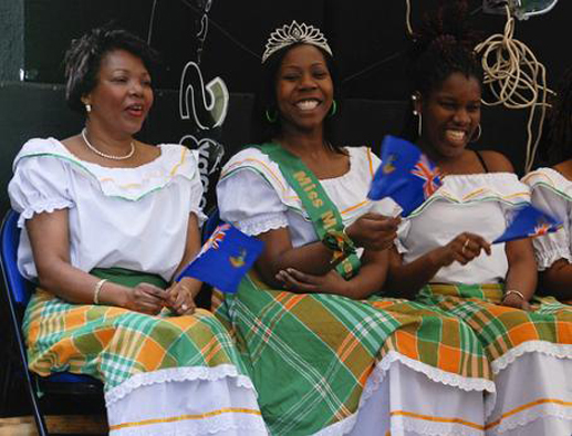 Miss Montserrat, center, with women wearing traditional green, orange, and white Montserratian dresses.