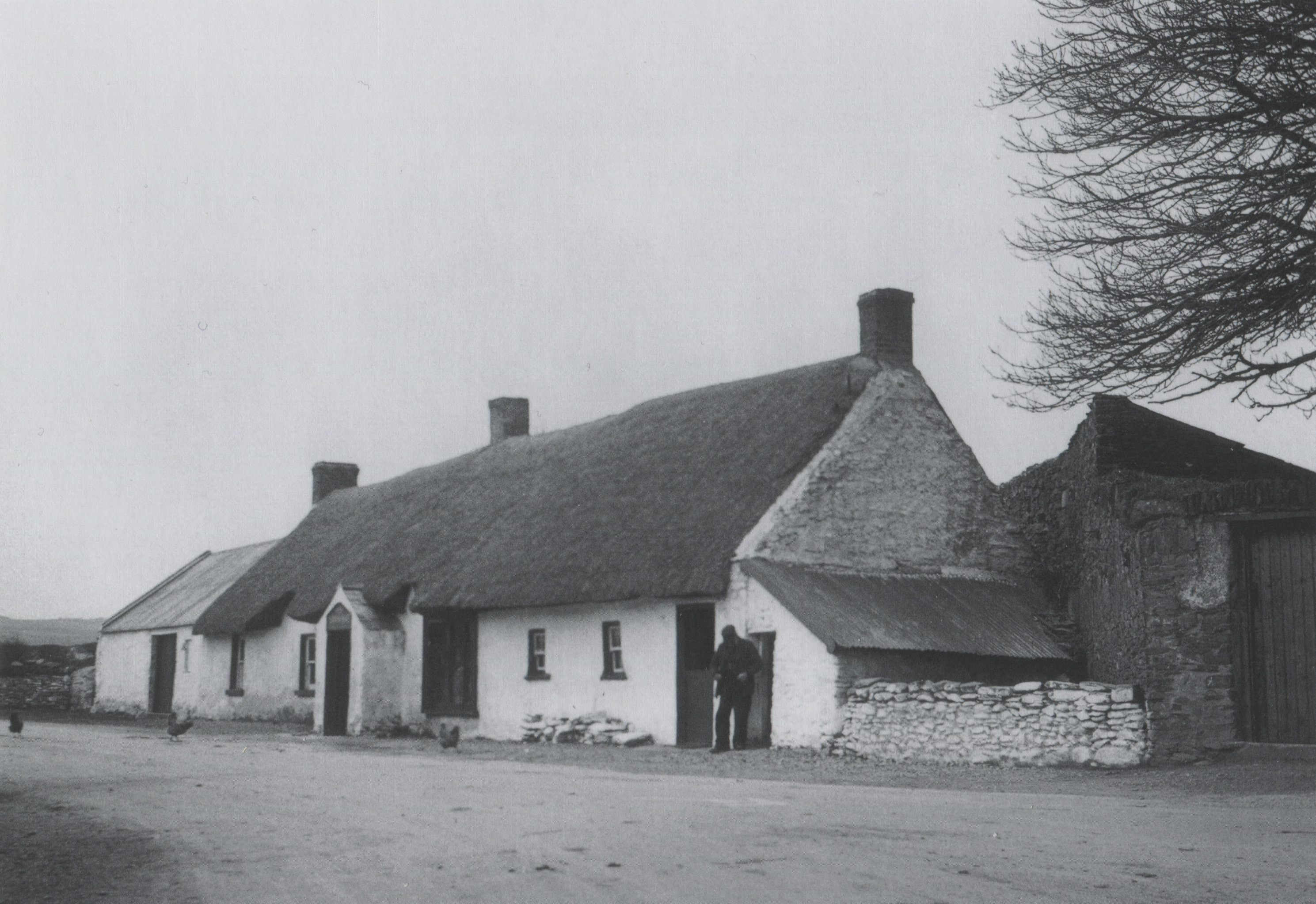 Thatched public house. Tall chimneys and low gables, along with the absence of súgán ropes, indicate that this is an inland location.