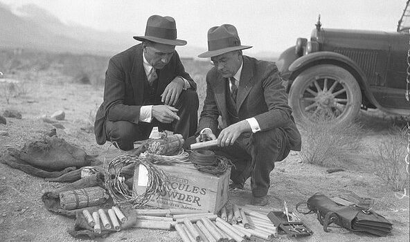 Two men examining kit of dynamite and wire found during sabotage incidents of Owens Valley Aqueduct, Southern California, circa 1924. Photo: Wikipedia