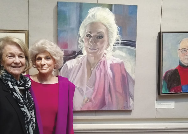 The artist Louise Peabody and singer Judy Collins pose in front of Peabody’s portrait of Collins at the Century Club.