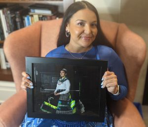 Cheyenne Lazore with photograph of Sky Timmons wearing the Ribbon Skirt that she created.